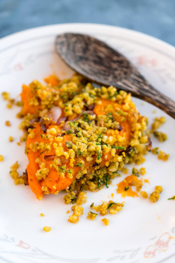 A scoop of savory sweet potato casserole on a plate garnished with parsley