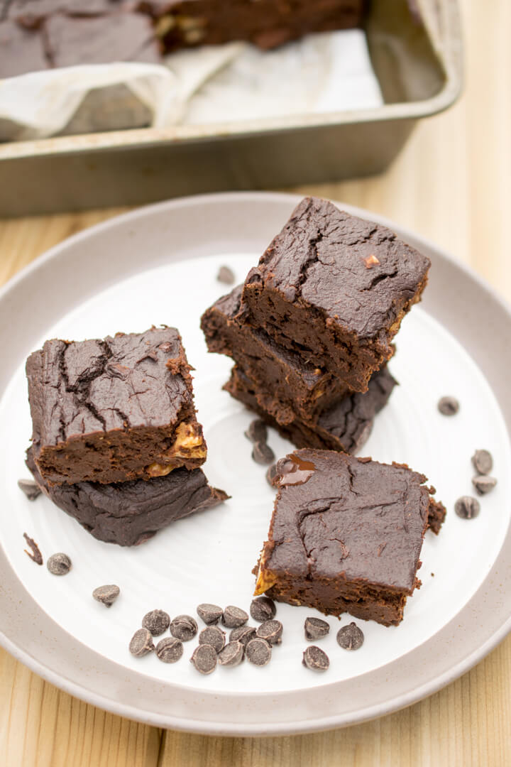 Vegan sweet potato-zucchini brownies stacked on a plate with chocolate chips