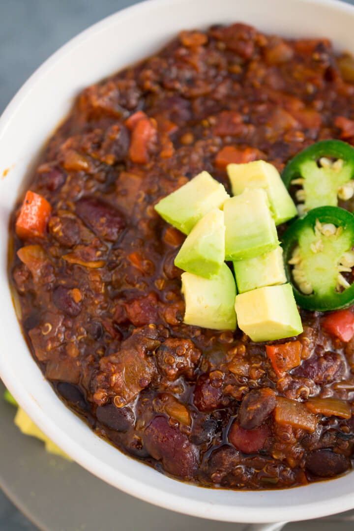 Close-up of quinoa chili showing the fluffy quinoa and the thick consistency of the stew, as well as beans and peppers, and rich reddish color.