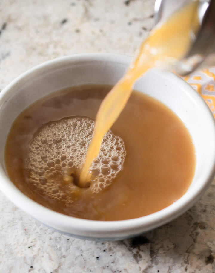 A bowl of vegan beef broth showing the dark, rich brown color