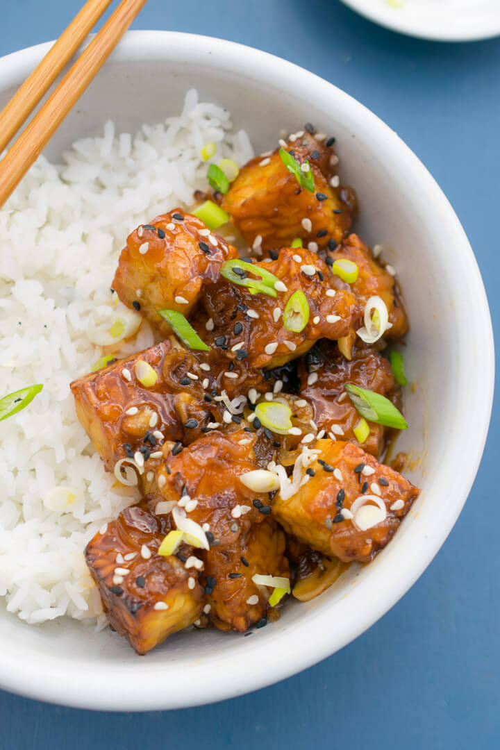 Mango tempeh in a bowl garnished with sesame seeds and scallions